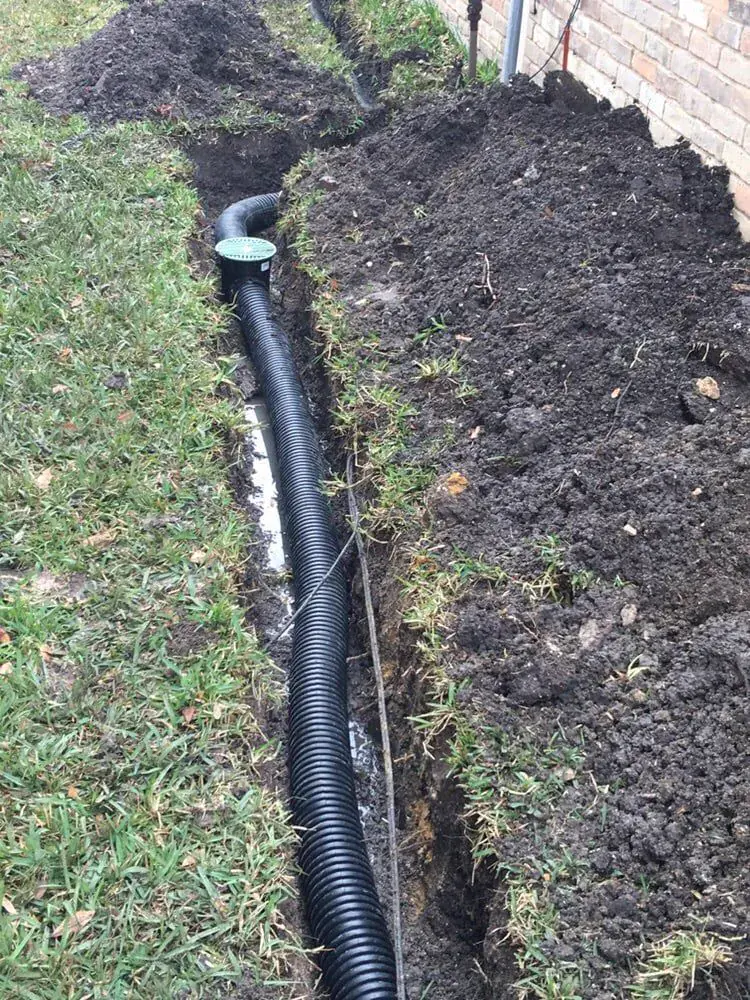 Residential drainage line installation beside a lawn